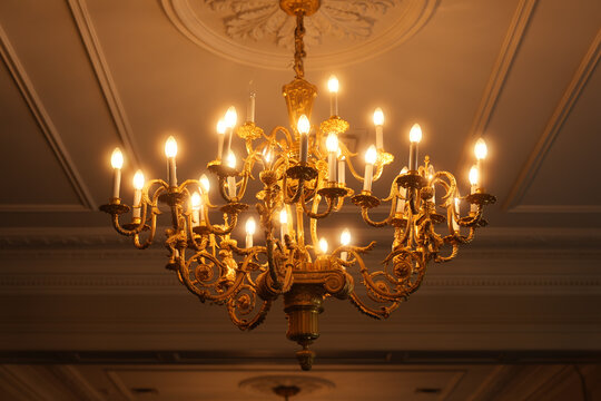 Elegant gold chandelier with glowing lights in ornate ceiling setting