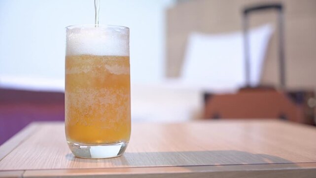 旅行先のホテルで缶ビールを注ぐ
