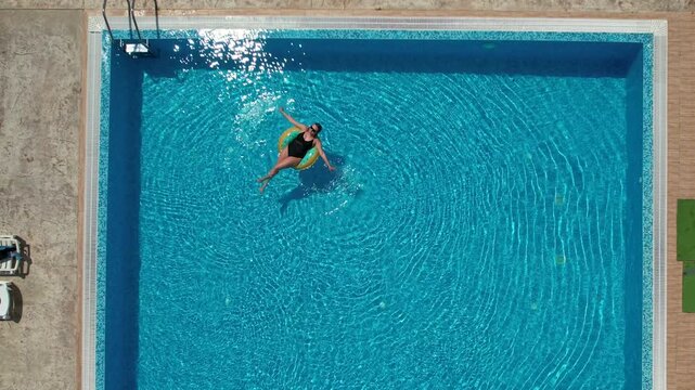 Woman on inflatable donut pool float in pool in hotel. Summer holidays, enjoying summer vacations
