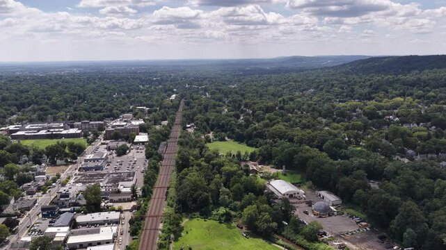 Descending camera tilt from the Essex County horizon toward railway tracks and green space
