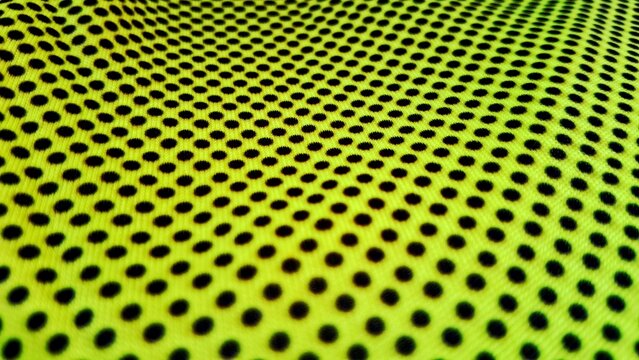Bright yellow athletic fabric featuring a repeating pattern of black dots