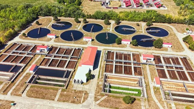 Several circular tanks are visible along with rectangular sections in a water treatment facility. The sunlight shows the layout of the area and equipment used.