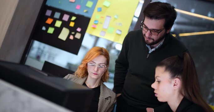 Team members discuss project ideas and work on computer tasks in a shared space during the afternoon hours