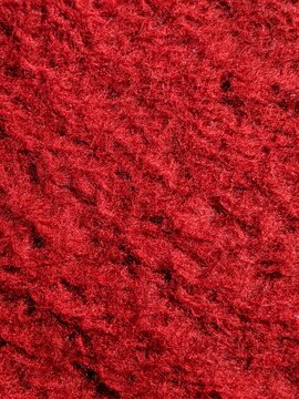 red carpet texture. Close-up of textured red fabric surface with fibrous details, highlighting irregular patterns and rich tactile depth.