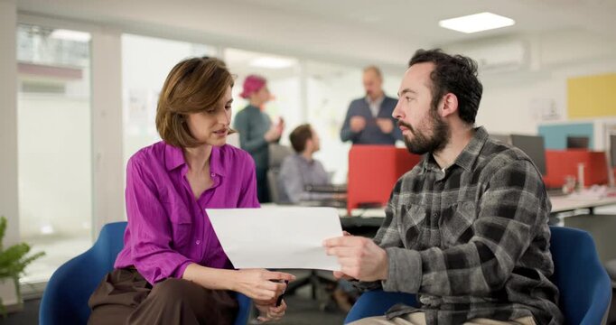 Business team members discuss project details in an office setting with focus on teamwork and collaboration during a busy workday