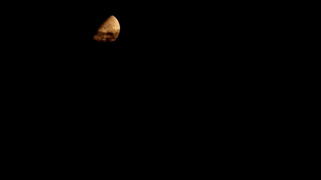 Tokyo,Japan - August 21, 2026: The half moon shining beyond thin clouds
