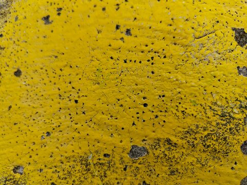 Yellow paint texture with organic black speckles, abstract urban background