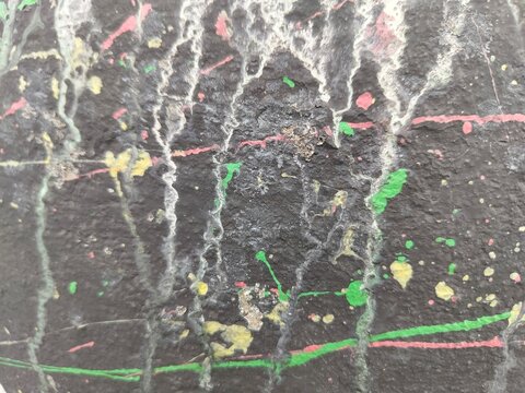 Dark textured wall with colorful paint drip lines, abstract urban background