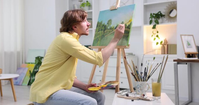 Man painting picture on easel in artist's studio