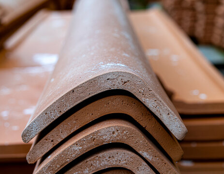 stacked terracotta ceramic ridge tiles and curved roof capping elements