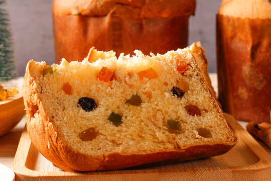 Closeup of a slice of traditional Christmas panettone, showing its soft, fluffy crumb and candied fruits, set on a rustic Christmas table