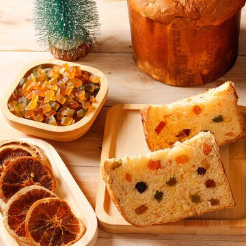 Slices of Christmas panettone with candied fruit and raisins on a bamboo tray, in a rustic Christmas arrangement