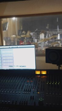 Analog equipment glows while musicians perform behind glass
