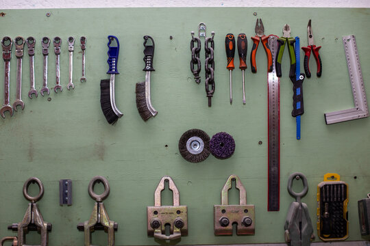 Car service tools organized on a green pegboard wall. Workshop equipment for automotive repair and maintenance in an auto workshop.