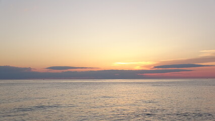 Obraz premium Sunrise over calm ocean horizon in East Sea. Scenic sunrise over the calm ocean horizon with colorful gradient sky and soft clouds in Gangneung, South Korea.