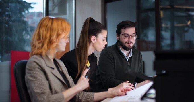 Group discussion about project planning in office setting with three team members collaborating on work tasks