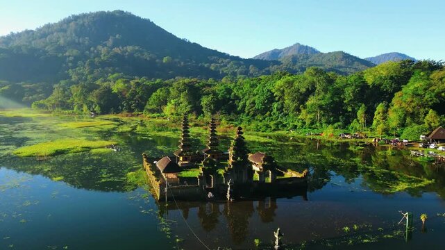 Scenic view of Gubug Temple at misty Lake Tamblingan surrounded by lush rainforest in Bedugul, Bali, Indonesia