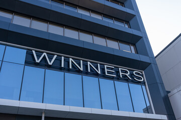 Fototapeta premium Toronto, ON, Canada - August 21, 2026: Closeup Winners logo sign on the building. Toronto, ON, Canada. Winners Merchants International LP is a chain of Canadian department stores owned by TJX.