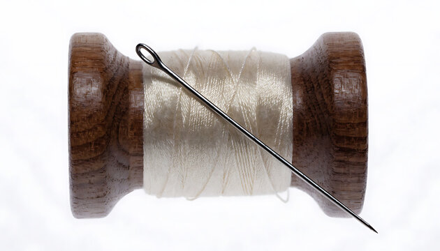 Vintage wooden spool with white thread and sewing needle isolated on white background