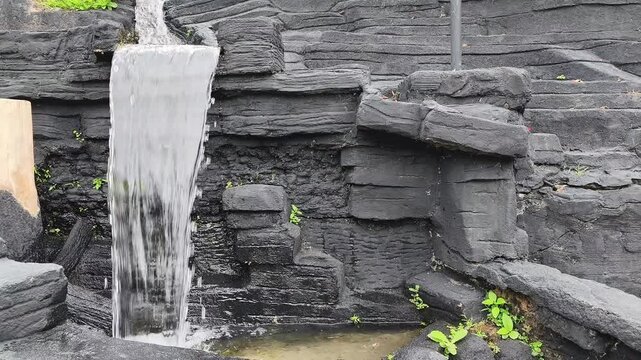 Artificial mini waterfall on old stone wall.