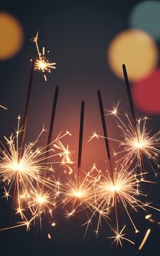 Burning sparkler sticks emitting bright sparks against a dark background with colorful bokeh lights