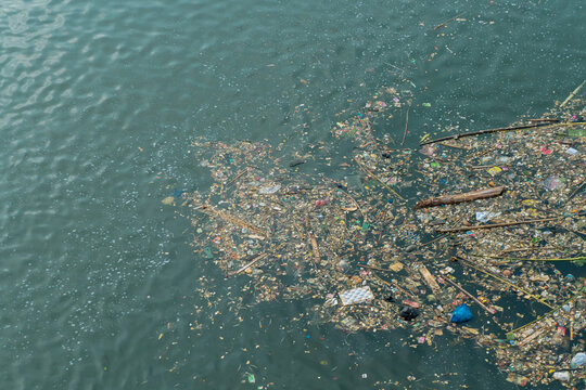 High view of various types of trash floating in and polluting the river, which dries up during the dry season.