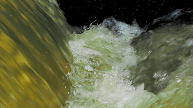 Close-up of dirty water flowing rapidly with white foam in drainage sewer pipe.