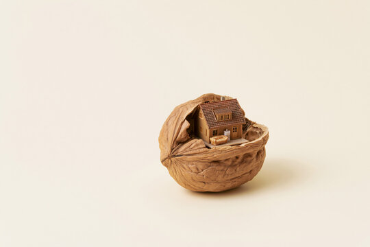 Walnut shell revealing a tiny house inside surreal scale concept