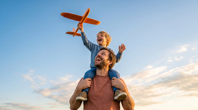 Father and Son Playing with Toy Airplane Outdoors Under a Blue Sky