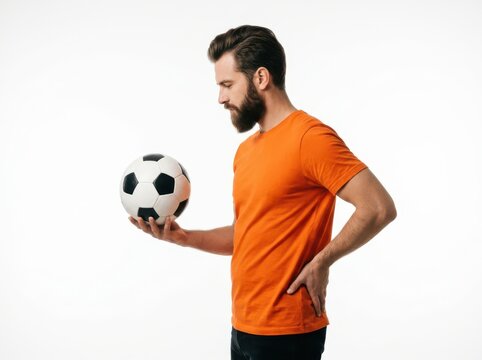 Side view of a bearded man in an orange tshirt holding a soccer ball isolated on white background