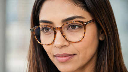 Obraz premium Detailed close portrait of a focused businesswoman wearing tortoiseshell glasses with sharp natural eyes and realistic skin texture