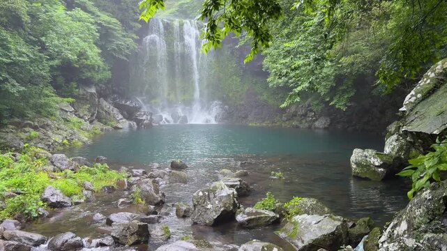 Cheonjeyeon waterfall plunging into a tranquil turquoise pond on jeju island