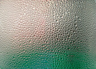 Obraz premium Background texture of stagnant water droplets. Condensate droplets on the surface of a plastic bottle, close-up view. Background of water drops on glass