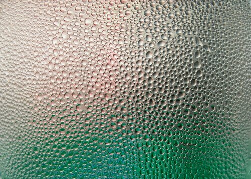 Background texture of stagnant water droplets. Condensate droplets on the surface of a plastic bottle, close-up view. Background of water drops on glass