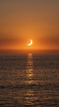 Breathtaking Partial Solar Eclipse Over a Calm Ocean at Sunset with Golden Light Reflection on Water