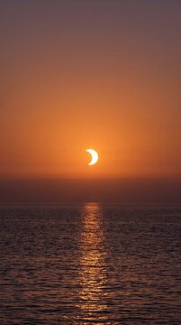 A Breathtaking Solar Eclipse Occurring During Sunset Over a Tranquil Ocean Horizon