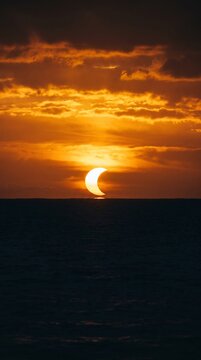 Crescent Solar Eclipse Sunset over Ocean Horizon with Dramatic Golden Sky