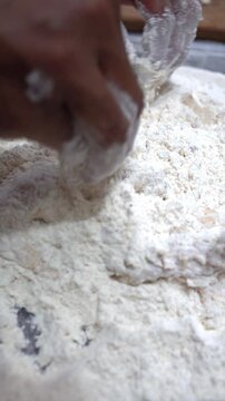Vertical close up of hands coating battered chicken with white flour for crispy fried chicken preparation