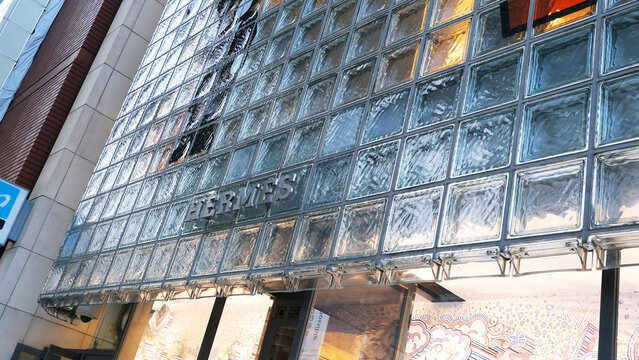 Tokyo, Japan on 28 September 2025: Herm&egrave;s flagship boutique in Ginza, featuring a signature glass block facade designed by Renzo Piano, with warm lighting glowing through the textured glass panel