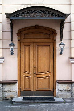 Classic double wooden front door with an arched transom, sheltered by a decorative black iron canopy.