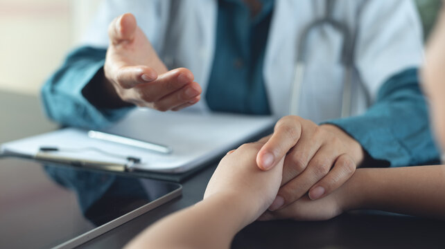 Female pediatrist doctor reassuring her young boy patient at medical clinic, healthcare and medicine concept.