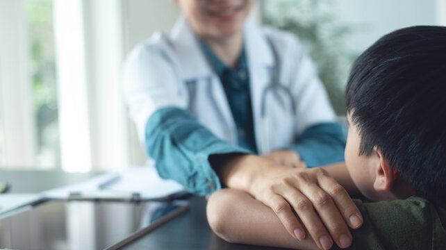Female pediatrist doctor reassuring her young boy patient at medical clinic, closeup
