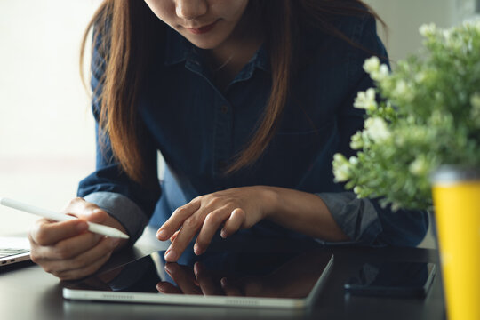 Business woman using digital tablet and laptop working at office, reading and proofing e-document via mobile app