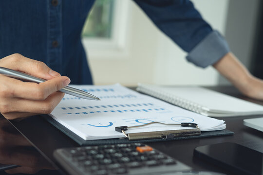 Business person analyzing financial report with paper document and calculator on office desk, close up