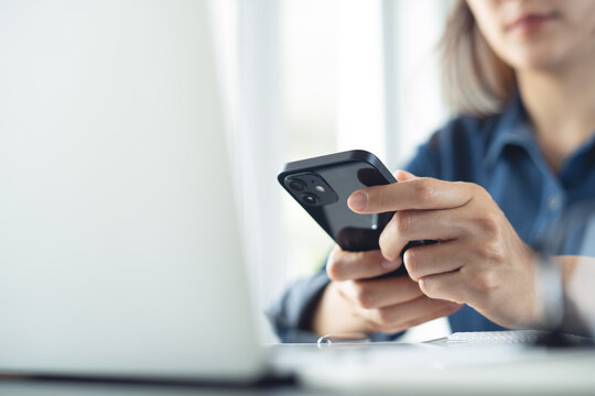 Business woman using smartphone during online working on laptop, surfing the net, searching the information at office. 