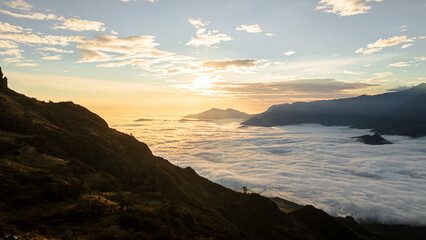 Obraz premium Andean sunset seen from Cerro Llipta in the district of Llama, Cajamarca, Peru. The setting sun illuminates a vast sea of ​​clouds covering the valleys surrounded by mountains in the distance