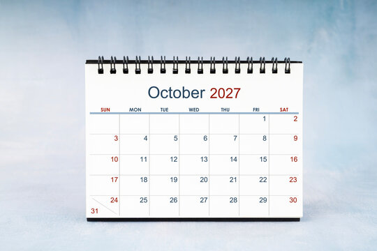 October 2027 Monthly desk calendar on vintage wall, Front view.