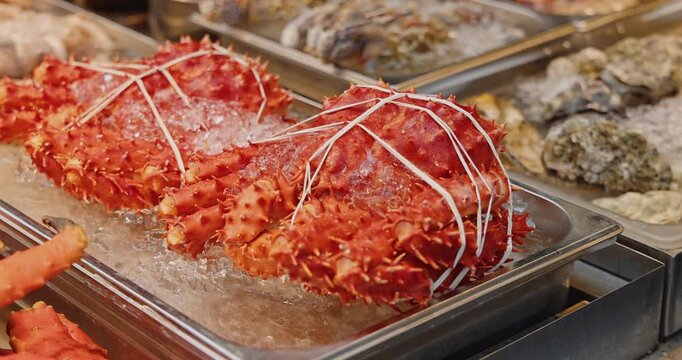 Red king crabs tied with string lying on crushed ice, fresh seafood market display, Paralithodes camtschaticus, commercial culinary retail.