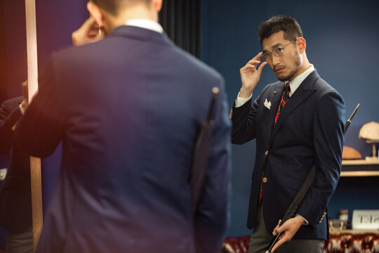 Man in Suit Adjusting Glasses in Mirror