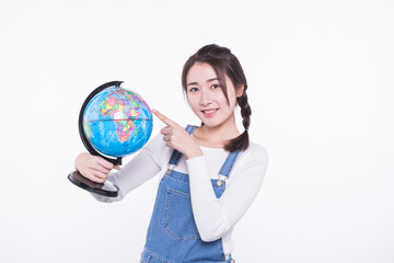 Fototapeta premium Young woman pointing at a globe isolated on white